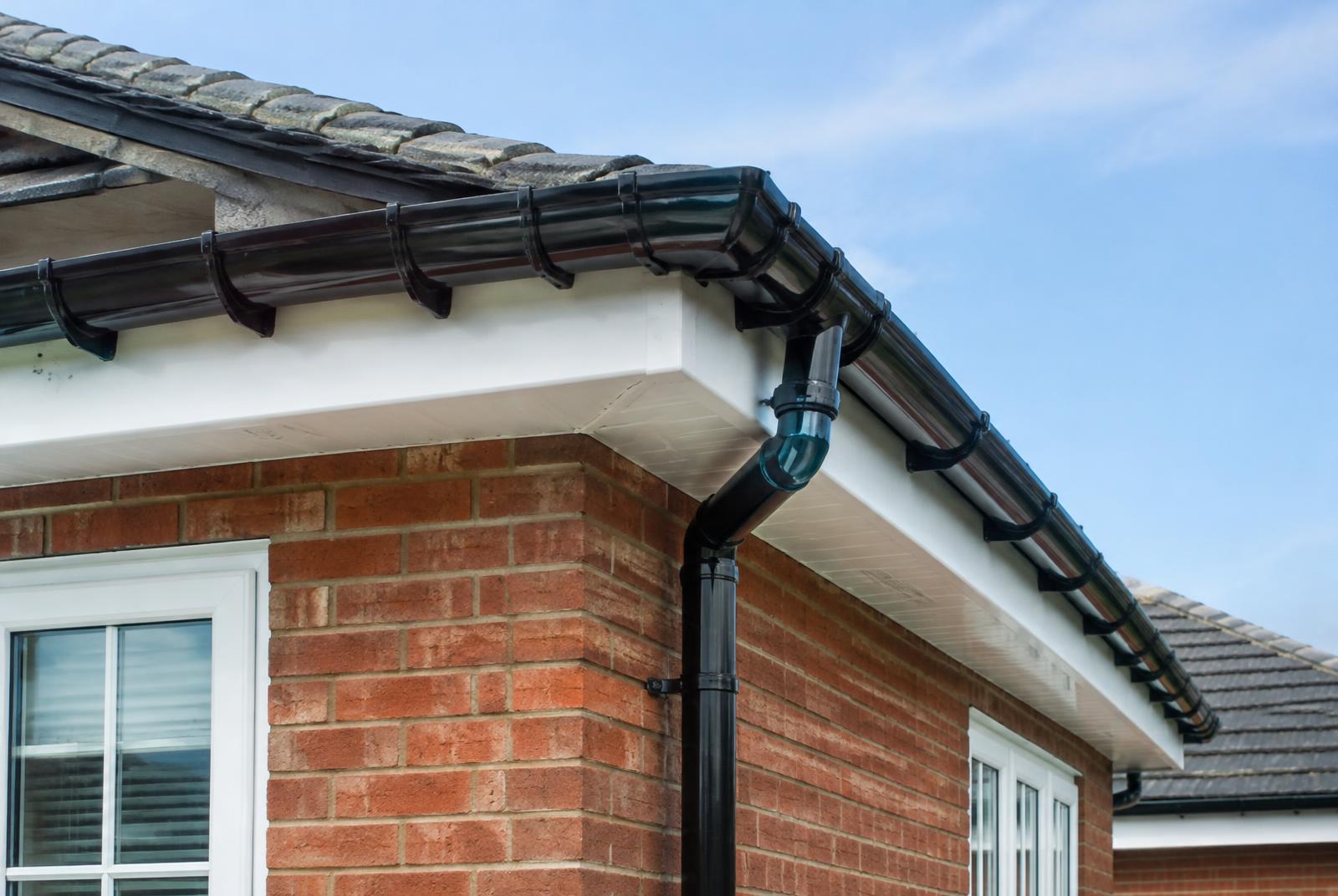 New black uPVC guttering and downpipe on a brick house with white fascia